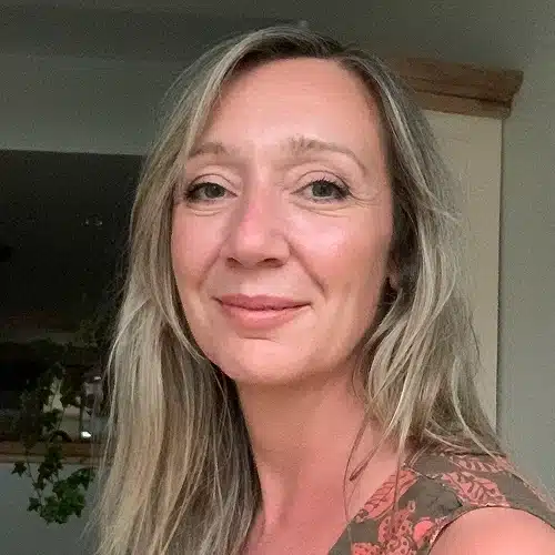 A woman with long, blonde hair and a slight smile looks at the camera. Indoors with a neutral background and greenery behind her, she wears a patterned top—capturing the creative spirit of the Kilkenny Animated Festival Team.