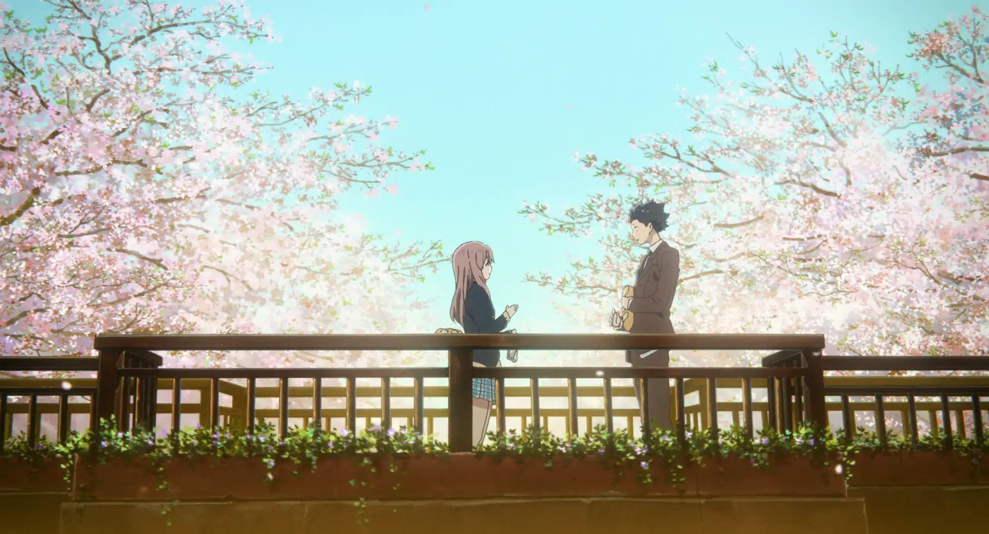 Two anime characters stand facing each other on a wooden bridge surrounded by cherry blossom trees in full bloom under a clear blue sky.