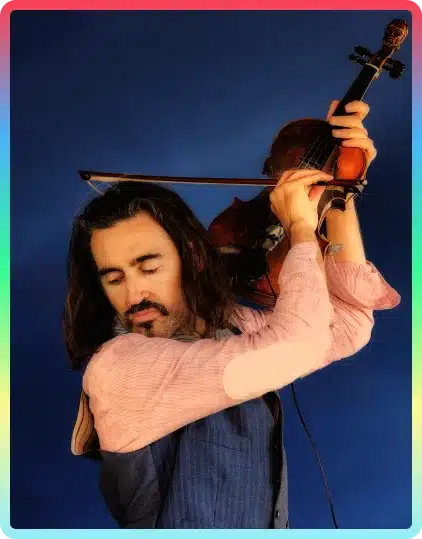 A man with long hair and a beard plays a violin dramatically with his eyes closed, wearing a blue waistcoat and pink shirt, against a blue background, capturing the creative spirit of the Kilkenny Animated Festival.