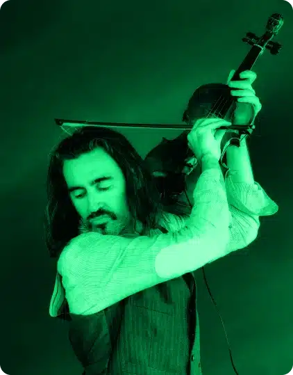 A person with long hair and a beard plays a violin passionately, eyes closed, holding the instrument high. The image, tinted green, captures the vibrant spirit of the Kilkenny Animated Festival.