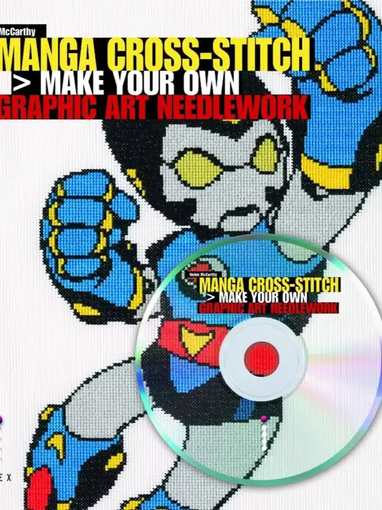 A cross-stitched character resembling a robot or superhero in blue and yellow is on a book cover titled "Manga Cross-Stitch." A CD labelled with the same title is placed over the bottom right corner.