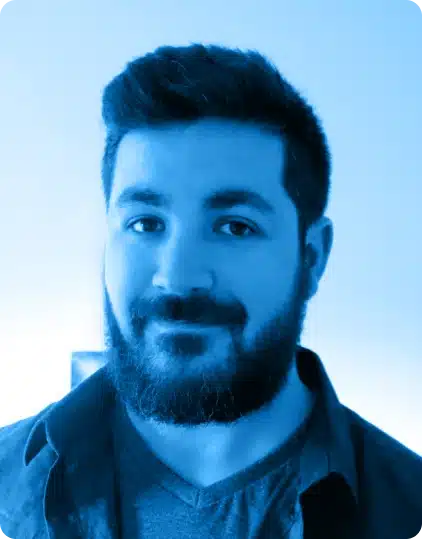 A bearded man with dark hair smiles slightly at the camera. He is wearing a dark shirt over a T-shirt. The image, featuring a blue colour filter and rounded corners, has a plain background—reminiscent of promotional portraits often seen for guests at the Kilkenny Animated Festival.