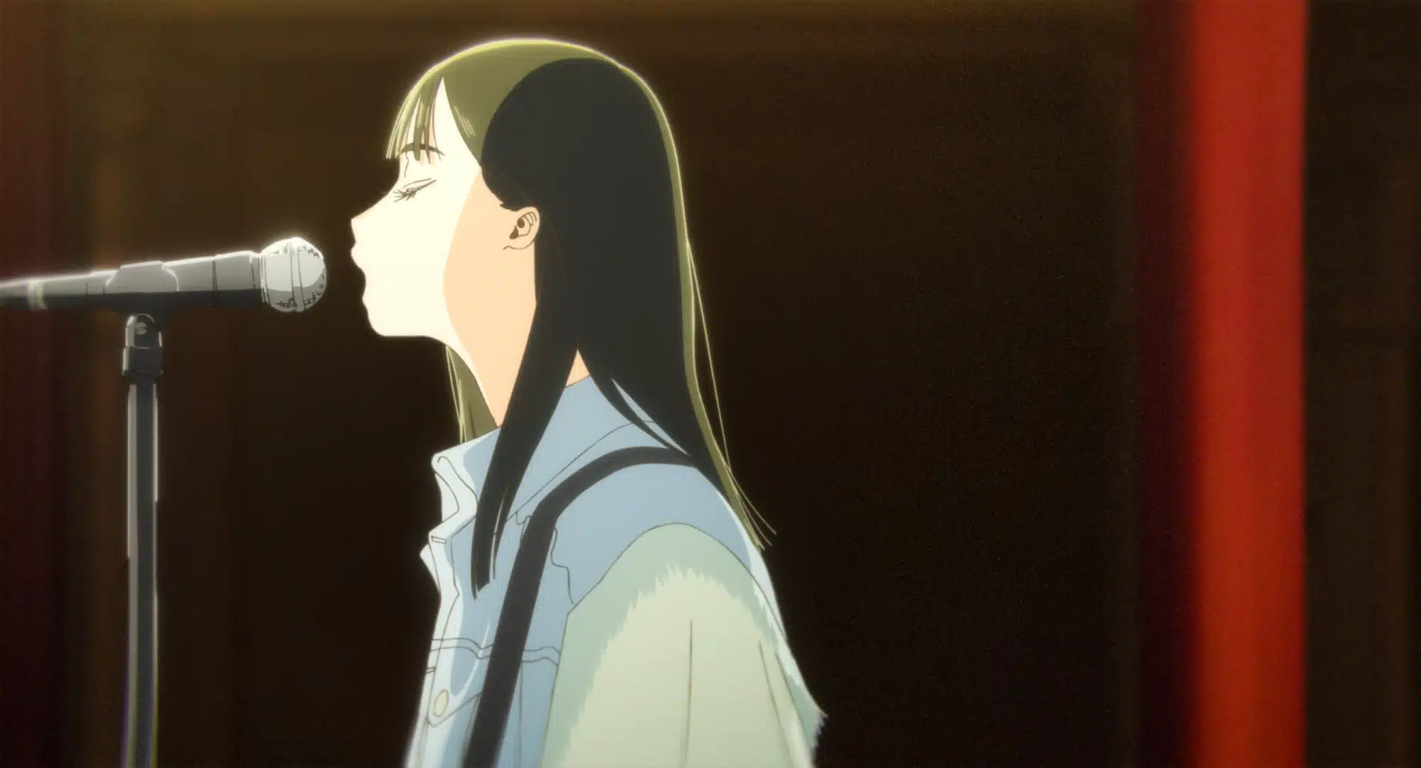 An animated girl with long dark hair and a light denim jacket sings into a microphone on stage, with a dark background highlighting her profile.