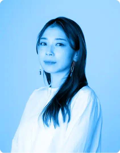A woman with long dark hair wearing a white top and dangling earrings poses against a plain, light blue background, evoking the creative spirit of the Kilkenny Animated Festival. The image has a blue colour filter.