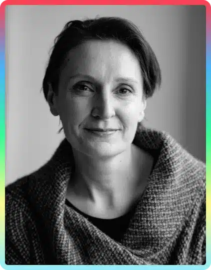 Black and white portrait of a person with short hair, wearing a textured jumper, looking at the camera with a slight smile. The photo has a colourful gradient border inspired by the vibrant energy of the Kilkenny Animated Festival.
