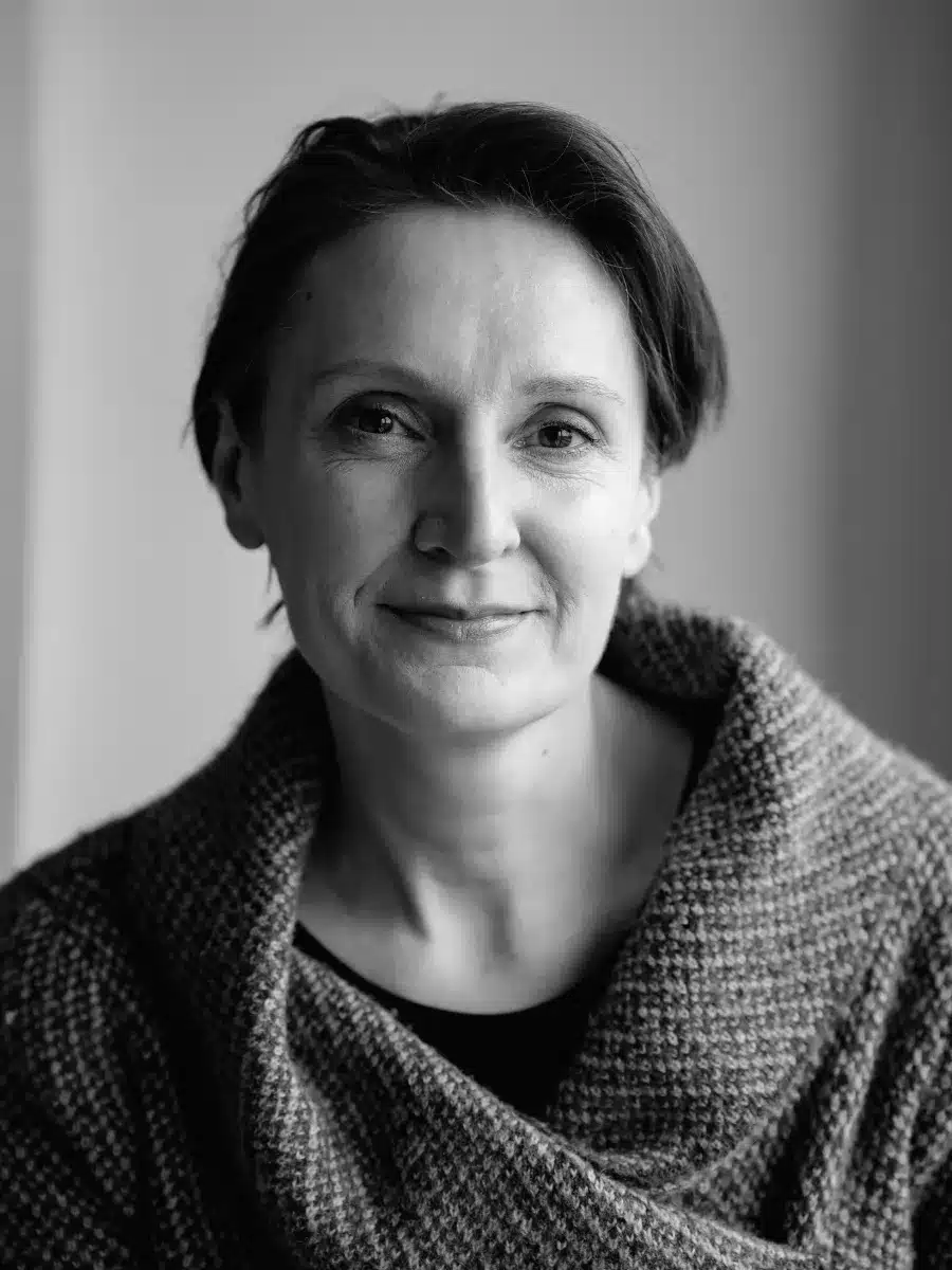 Black and white portrait of a middle-aged woman with short hair wearing a textured, knitted jumper, looking at the camera with a soft, neutral expression.
