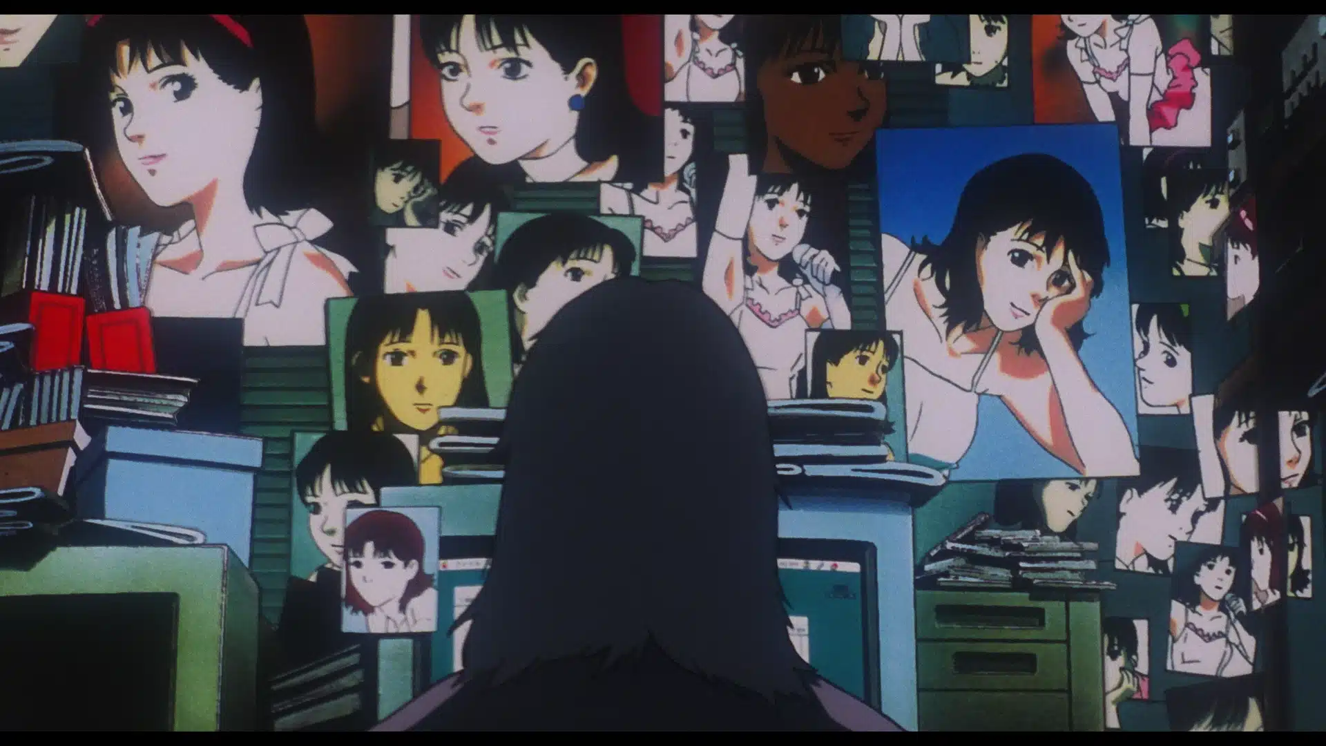 A person with dark hair faces a cluttered wall and desk, covered with stacks of papers and many photos of a young woman in various poses.