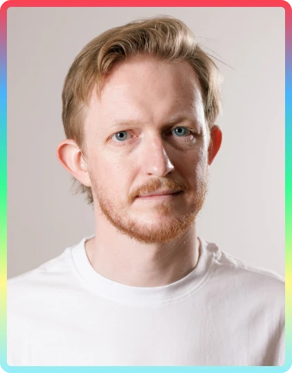 A man with light skin, short blond hair, and a beard wears a plain white shirt, standing against a neutral background with a soft rainbow-coloured border around the image—capturing the creative spirit of the Kilkenny Animated Festival.