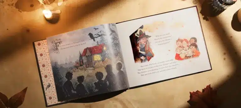 An open storybook on a table shows illustrated children looking at a house on one page, and a witch reading to children on the other. Candles, leaves, and biscuits surround the book.